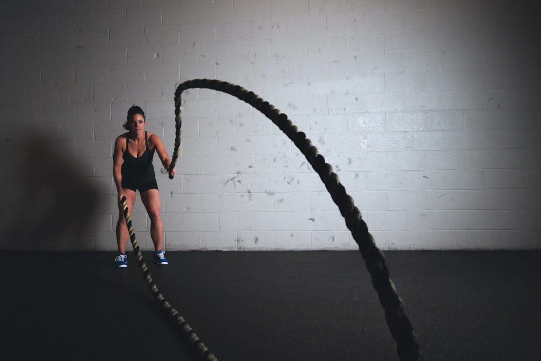 Woman doing battle rope strength and cardio training as part of a balanced fitness portfolio